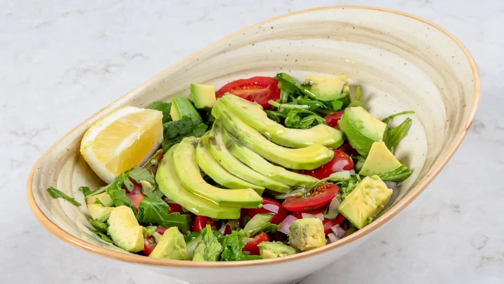 Vegan avocado salad with cherry tomatoes, arugula, red onion and lemon, one of the vegetarian Mediterranean restaurant options